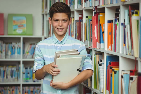 Portret van schooljongen houden boeken in bibliotheek — Stockfoto