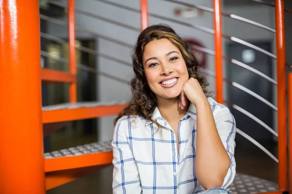 Glimlachend vrouwelijke uitvoerende zittend op trap in kantoor — Stockfoto