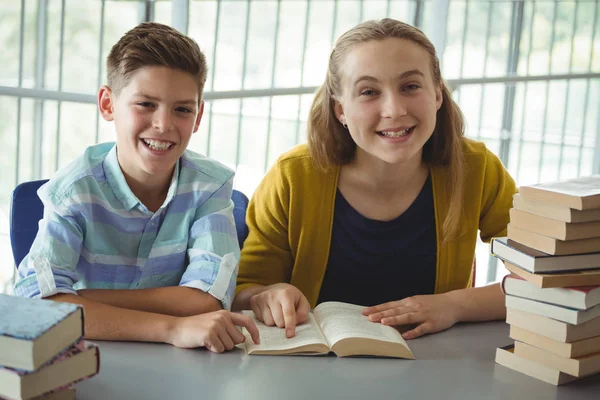 Des écoliers souriants lisent des livres à la bibliothèque de l'école — Photo