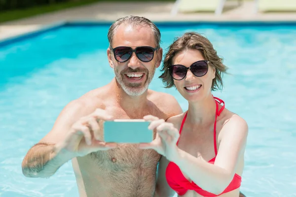 Couple taking selfie from phone in pool — Stock Photo, Image