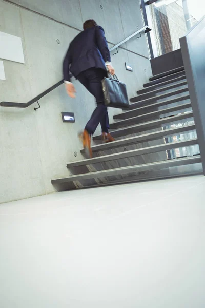 Businessman climbing stairs at office — Stock Photo, Image