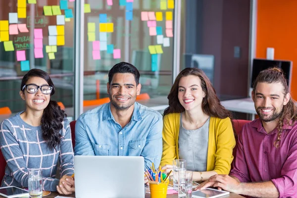 Sonrientes diseñadores gráficos discutiendo sobre portátil en la reunión —  Fotos de Stock