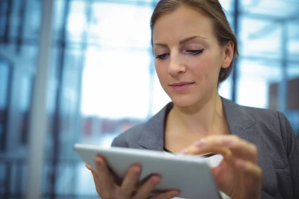 Mujer de negocios atenta utilizando tableta digital en el pasillo —  Fotos de Stock