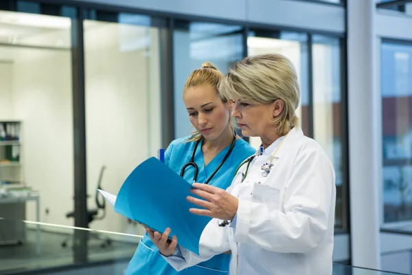 Médico e enfermeiro a olhar para um relatório médico — Fotografia de Stock