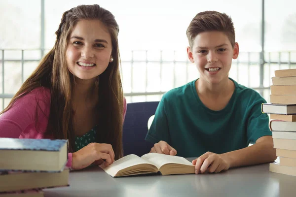 Crianças da escola sorrindo lendo livros na biblioteca da escola — Fotografia de Stock