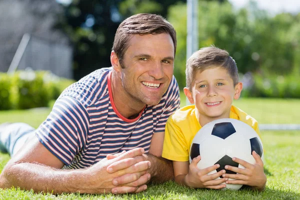 Father and son lying on grass in the park — Stock Photo, Image