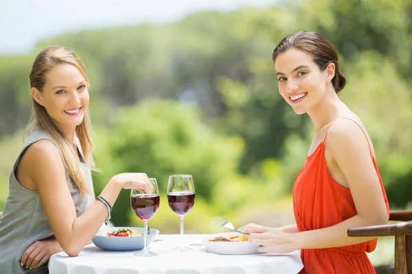 Amigos felizes sorrindo enquanto comem no restaurante — Fotografia de Stock