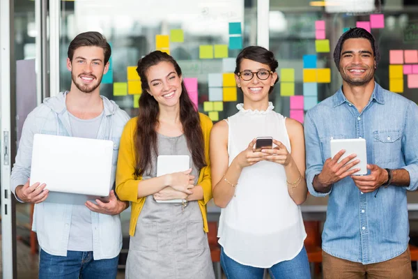 Ritratto di dirigenti sorridenti che utilizzano laptop, telefono cellulare e tablet digitale — Foto Stock