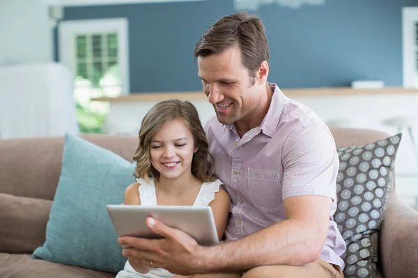 Pai e filha sentados no sofá usando tablet — Fotografia de Stock