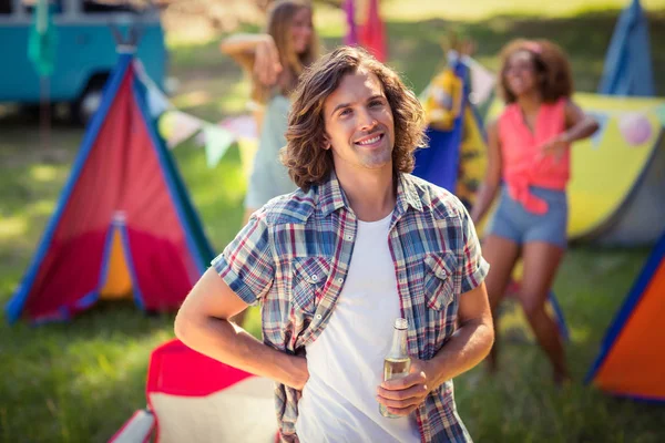Ritratto di uomo che tiene una bottiglia di birra al campeggio — Foto Stock