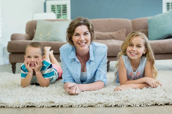 Mãe com filho e filha deitados no tapete — Fotografia de Stock