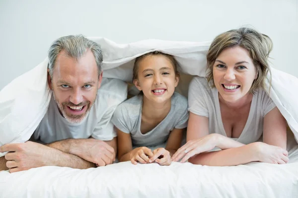 Familjen liggande under filt på säng — Stockfoto