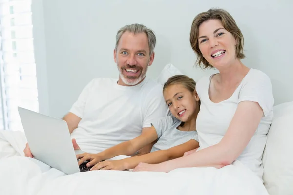 Rodinu pomocí přenosného počítače na lůžku v ložnici — Stock fotografie