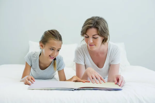 Mother and daughter on bed and reading book — Stock Photo, Image