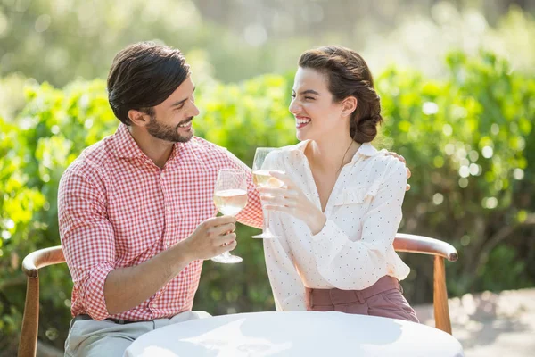 Casal brindar copos de vinho enquanto sentado — Fotografia de Stock