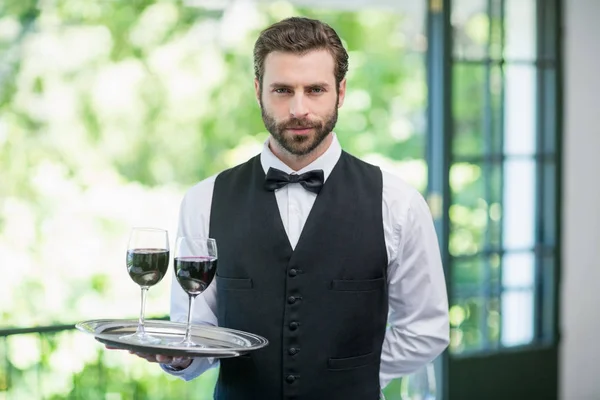 Мужчина официант держит поднос с бокалами для вина — стоковое фото