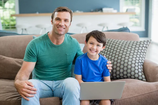 Vater und Sohn sitzen mit Laptop auf Sofa — Stockfoto