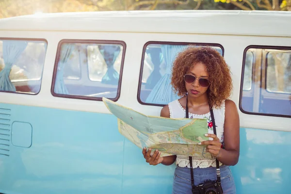 Woman leaning on campervan and looking at map — Stock Photo, Image