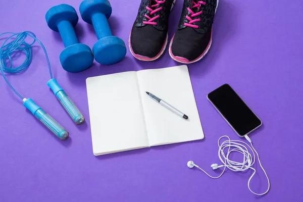 Acessórios de fitness com livro aberto e telefone móvel — Fotografia de Stock