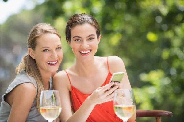 Friends laughing while using mobile phone in the restaurant — Stock Photo, Image