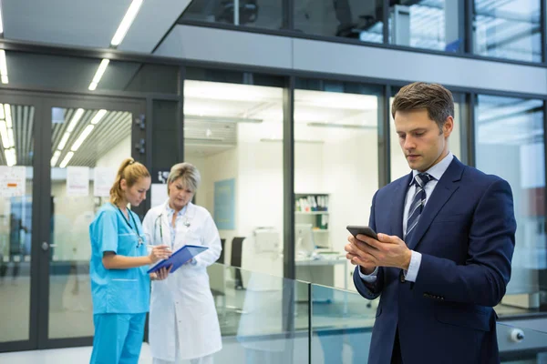 Uomo d'affari utilizzando cellulare mentre il medico e l'infermiere discutono — Foto Stock