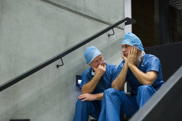 Worried male surgeons sitting on staircase — Stock Photo, Image