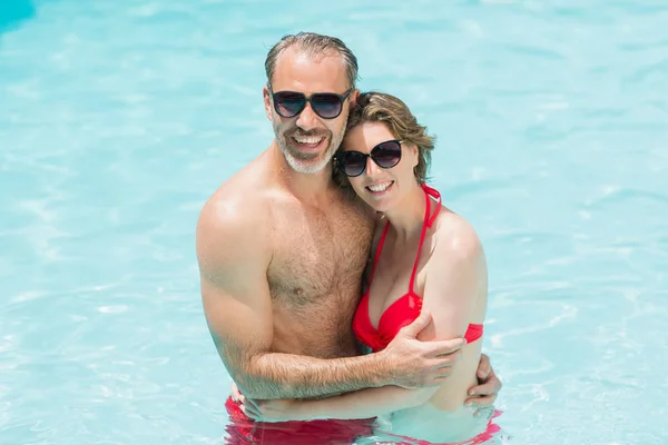 Pareja romántica abrazándose en la piscina sonriente — Foto de Stock