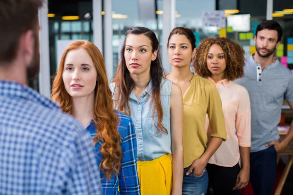 Serious colleagues standing in front of male executive — Stock Photo, Image