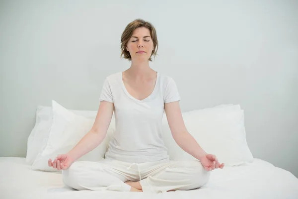 Mujer haciendo meditación en la cama en el dormitorio —  Fotos de Stock