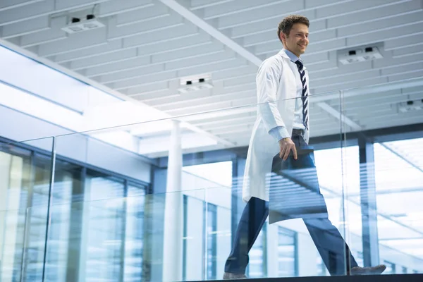 Médico varón caminando con informe de rayos X en corredor —  Fotos de Stock