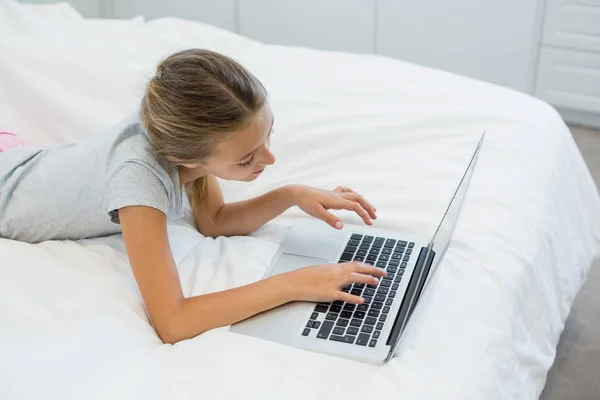Fille couchée sur le lit et utilisant un ordinateur portable — Photo