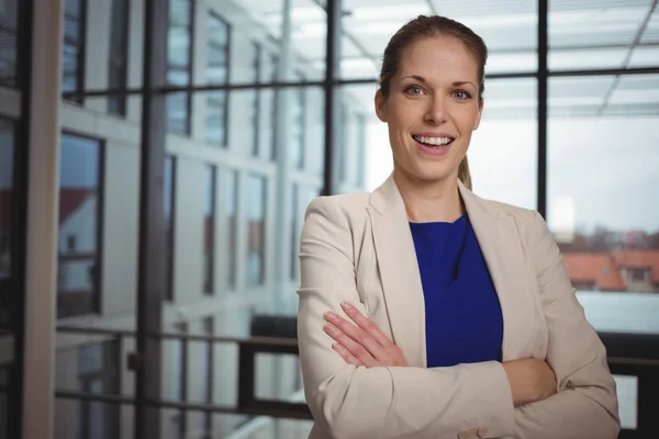 Portrait of beautiful businesswoman standing with arms crossed in corridor — Stock Photo, Image