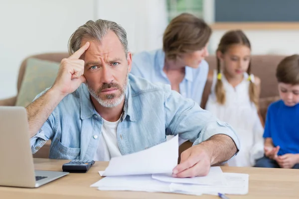 Bezorgd mens berekening van rekeningen op laptop — Stockfoto