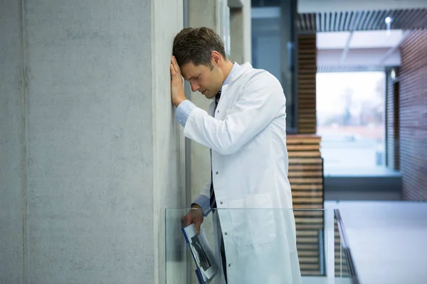 Orolig för manliga läkare lutande på väggen nära korridor — Stockfoto