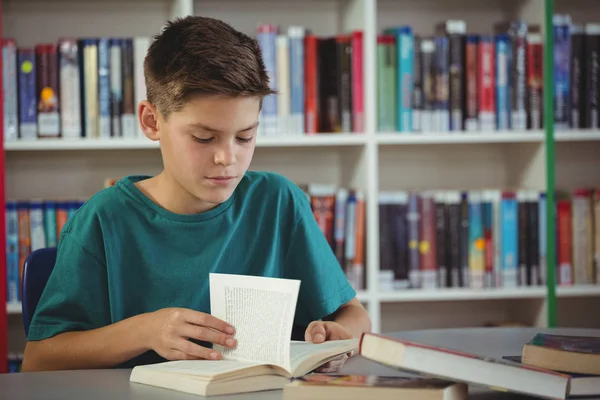Attente schooljongen leesboek in bibliotheek — Stockfoto