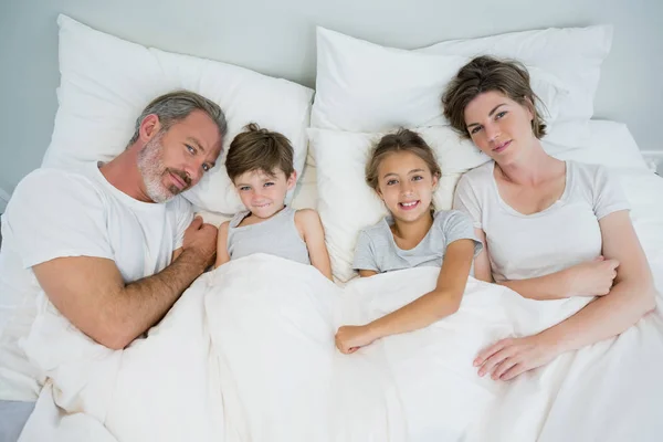 Family lying together on bed in bedroom — Stock Photo, Image