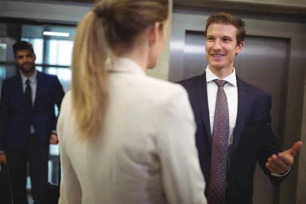 Üzletember egymásra hatók-val a női kollégája közelében lift — Stock Fotó