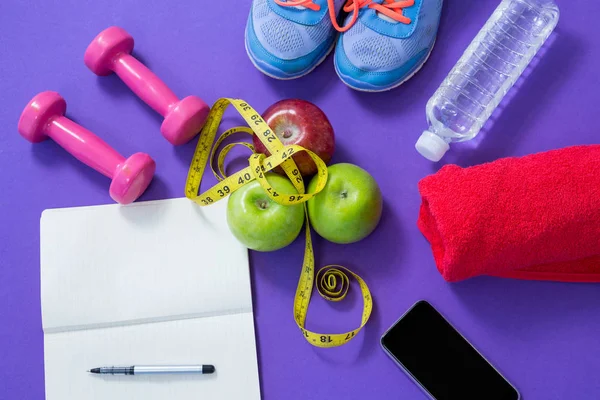 Acessórios de fitness com livro aberto, maçãs, telefone celular e fita métrica — Fotografia de Stock