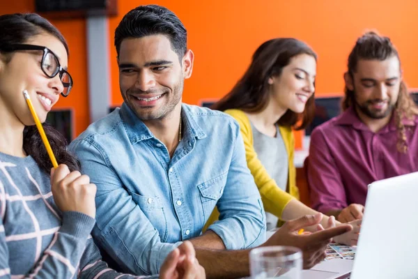 Sonrientes diseñadores gráficos discutiendo sobre portátil en la reunión — Foto de Stock