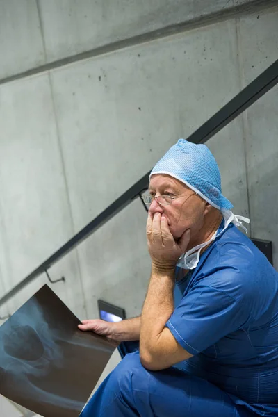 Worried male surgeon holding x-ray on staircase — Stock Photo, Image