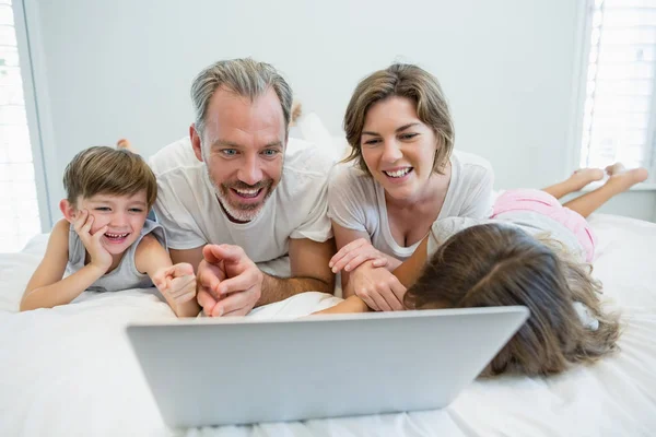 Famiglia con computer portatile sul letto in camera da letto — Foto Stock