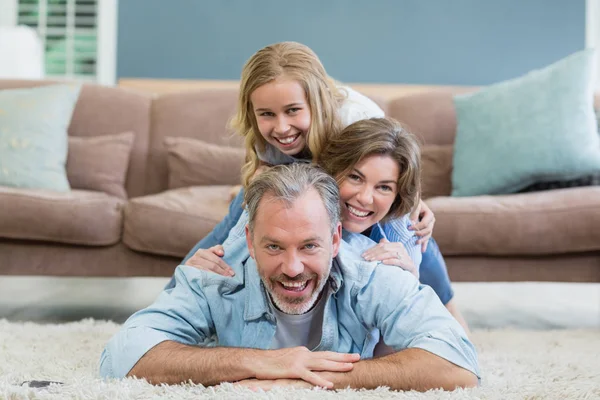 Familie liegt gehäuft auf Teppich im Wohnzimmer — Stockfoto