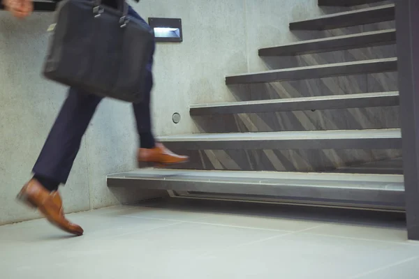 Empresario subiendo escaleras en la oficina — Foto de Stock