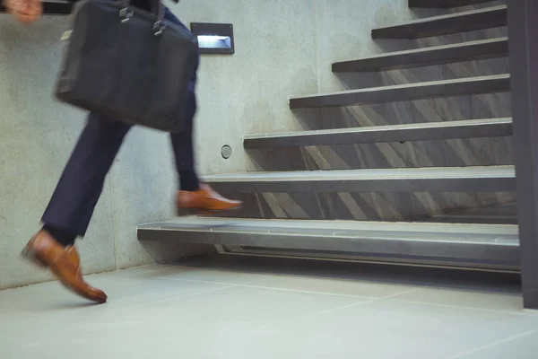 Businessman climbing stairs at office — Stock Photo, Image