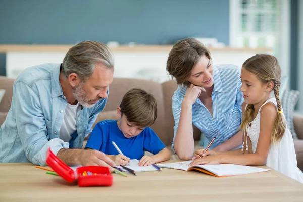 Geschwister bekommen Hilfe bei Hausaufgaben von Eltern — Stockfoto