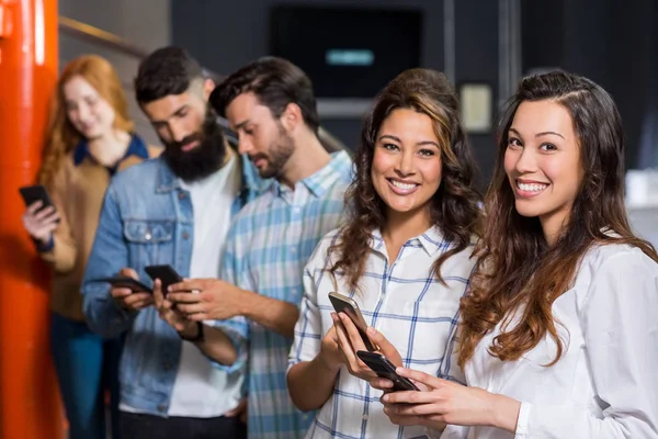 Happy male and female executive using mobile phone in office — Stock Photo, Image