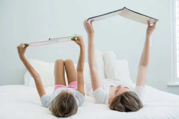 Mère et fille au lit et livre de lecture — Photo