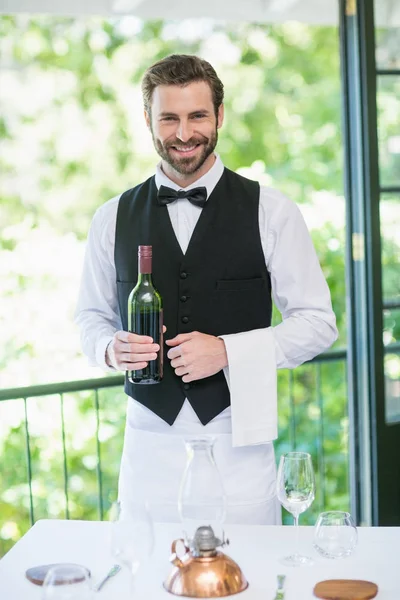 Male waiter holding bottle of wine — Stock Photo, Image