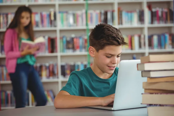 Écolier utilisant un ordinateur portable dans la bibliothèque — Photo