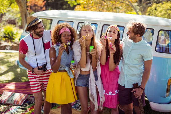 Group of friends blowing bubbles from bubble wand in park — Stock Photo, Image